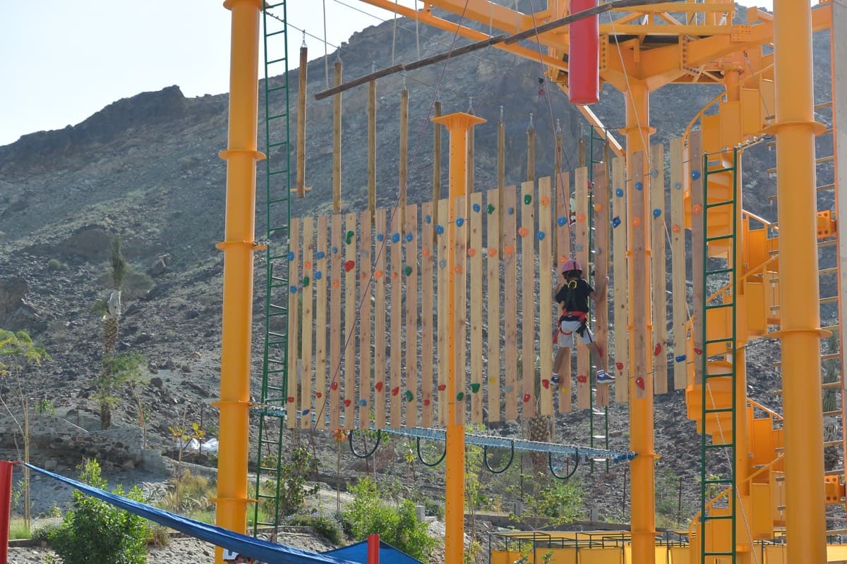 A student crossing a high ropes course in the mountains